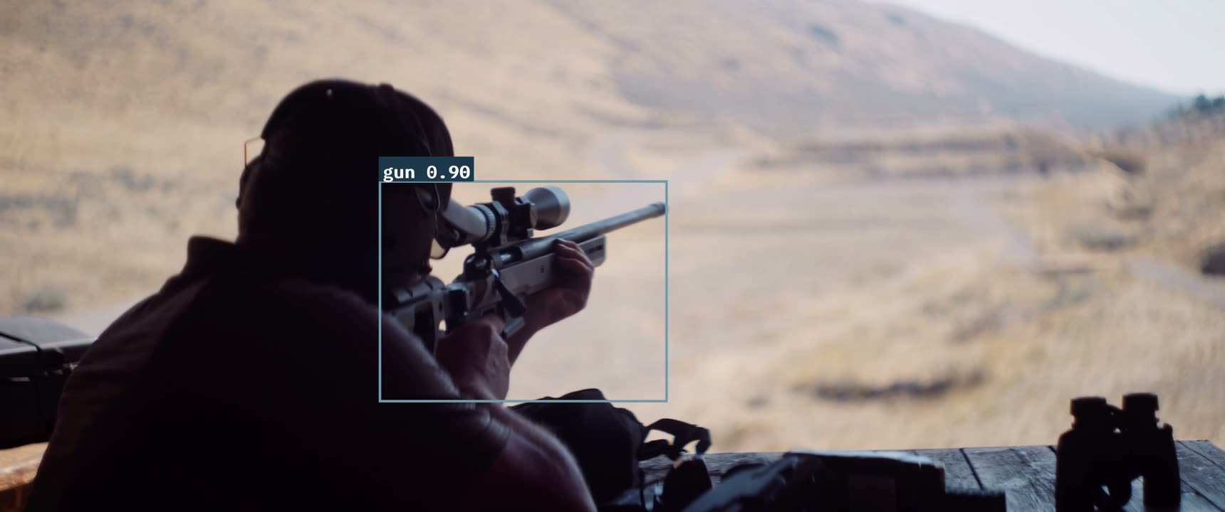 A single frame with a detection box labelled gun 0.90 drawn around a rifle.